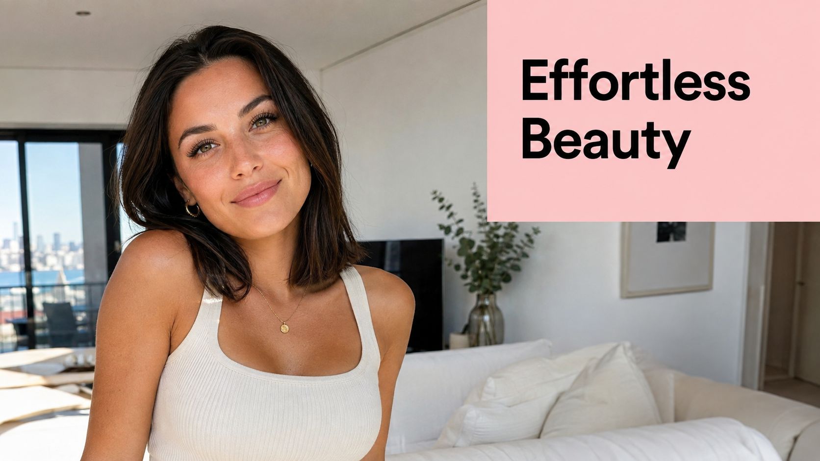 Natural Lash Extension Guide for a Subtle Sydney Look 2 A beautiful woman with natural features smiling in a bright, modern living room setting.
